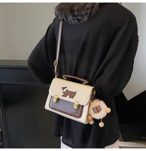 Detail of beige and brown crossbody bag featuring a dachshund patch and plush charm