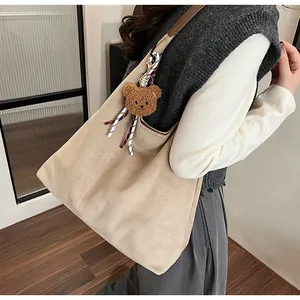 Chic beige suede hobo bag with brown shoulder strap and cute teddy bear charm