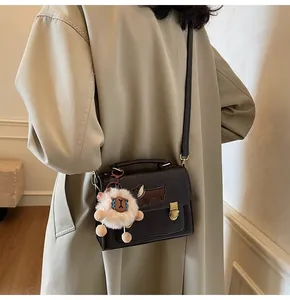 Detail of dark brown square bag with dachshund embroidery and white fluffy sheep pendant