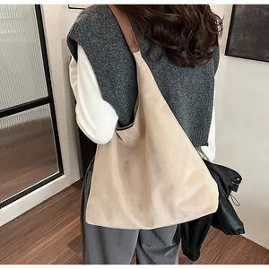 Detail of minimalist hobo bag with khaki suede texture and dark brown leather strap