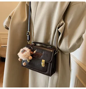 Detailed view of deep brown vintage square bag with dog patch and plush lamb charm