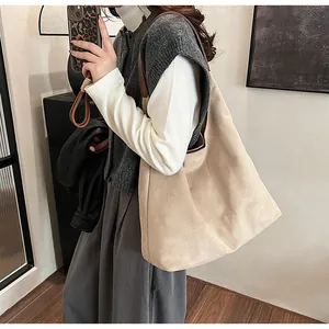 Close-up of the large beige suede tote bag with brown leather handles worn on shoulder