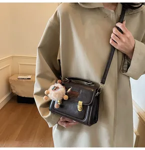 Detail view of dark brown vintage crossbody bag with cute puppy motif and plush sheep charm