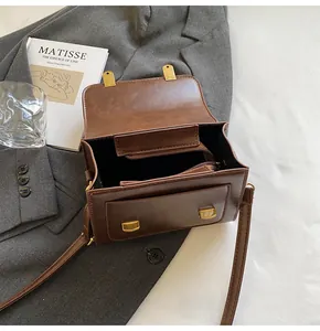 Detailed interior of brown leather handbag featuring central zipper and golden buckle