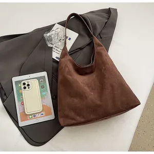 Flat lay of a large dark brown suede tote bag with professional lifestyle accessories