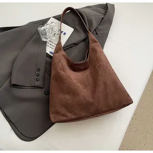 Macro view of the soft brown suede texture and minimalist curved handle of the tote bag