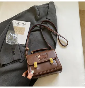 Close-up of brown retro square bag with embroidered dachshund and gold vintage buckles