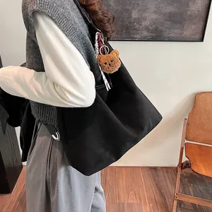 Minimalist black canvas tote bag with a cute bear charm, ideal for daily commute or school