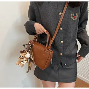 Detail einer braunen Boston-Tasche aus Leder mit Bärenanhänger und Schultergurt