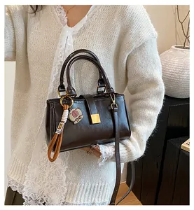 Detail view of vintage dark brown leather handbag with gold buckle and pig charm
