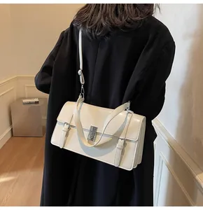 Vue détaillée d'un sac à rabat blanc crème porté sur un manteau en laine noir chic