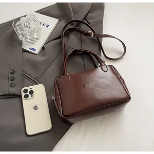 Detailansicht der dunkelbraunen Lederhandtasche auf einem grauen Blazer für den Büro-Look