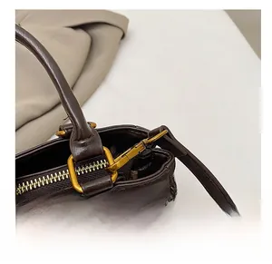 Close-up of premium gold-toned metal hooks and hardware on a dark brown leather handbag