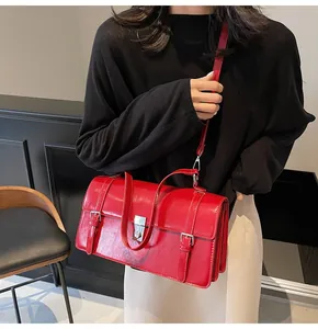 Gros plan d'un sac messager rouge avec fermoir argenté sur une chaise noire