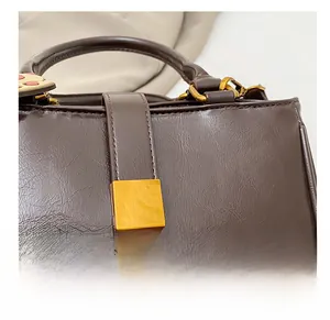 Close-up of golden metal buckle and textured leather on a dark brown handbag