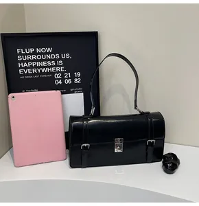 Détail du sac messager noir avec fermoir argenté à côté d'une tablette pour comparer la taille