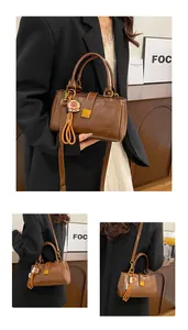 Detail of brown leather tote bag featuring a gold metal clasp and a cute piglet pendant