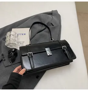 Détail du sac à main noir verni avec fermoir métallique argenté et boucles décoratives