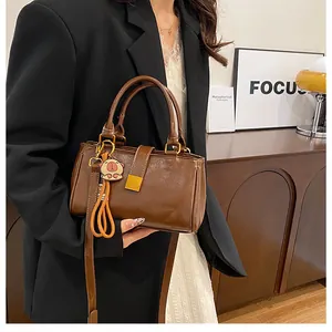 Brown patent leather handbag with metal buckle and pig charm shown in modern interior