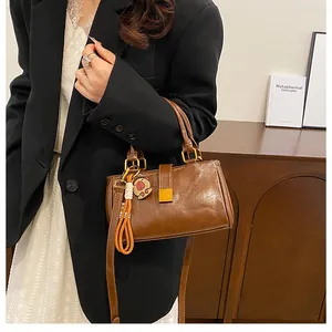 Brown vintage faux leather handbag with a bear charm and gold buckle worn by a model