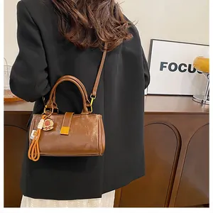 Detail of a retro dark brown leather crossbody bag with gold lock and charm