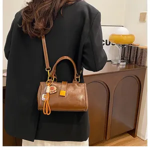 Detail of a brown leather shoulder bag with a gold lock and a cute bear bag charm accessory