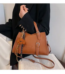 Detail shot of a brown vintage leather tote bag with metal buckles and a plush dog charm