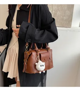 Dettaglio della borsa in pelle marrone con ciondolo a pecora di peluche e tasca anteriore
