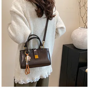 Detailed macro view of dark brown leather handbag featuring gold buckle and cute plush charm