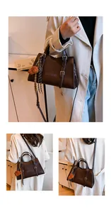 Detail of a large brown tote bag with leather texture, brand logo, and dog charm