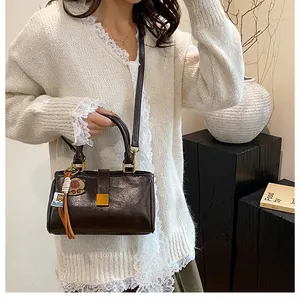 Detail of dark brown leather handbag featuring golden buckle and cute bear tassel charm