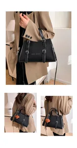 Detail view of black tote bag featuring decorative silver buckles and embossed branding