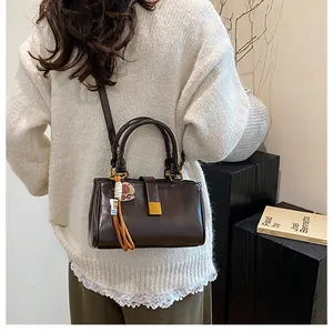 Detail of dark brown leather crossbody bag with gold lock and decorative charm charm