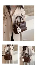 Dettaglio della borsa retrò in pelle marrone scuro con ciondolo in peluche bianco