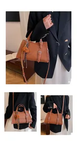 Detailed view of brown lychee-grain leather tote bag with stylish teddy bear keychain