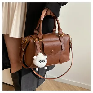 Dettaglio borsa Boston marrone retrò con trama in pelle e ciondolo di peluche su modella