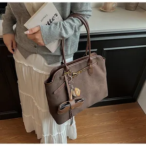 Brown suede tote bag detail with cute pastry charm and leather eyewear case accessory