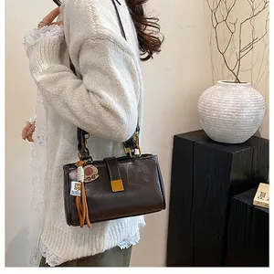 Detail of dark brown leather handbag with gold buckle and cute animal charm on the strap