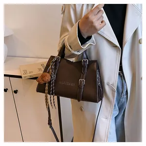 Detail of coffee brown PU leather tote bag with metallic buckles and plush dog charm