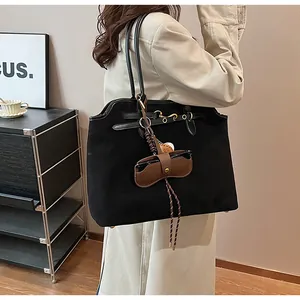 Detailed close-up of large black suede tote bag with brown leather sunglasses charm
