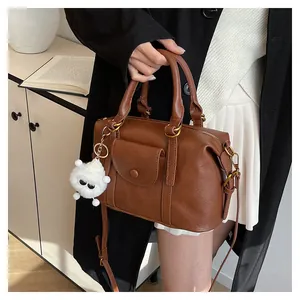 Dettaglio borsa a mano marrone in pelle con ciondolo peluche e tasca con patta magnetica