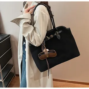 Close-up of black suede tote bag with gold hardware and leather eyewear pouch accessory