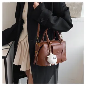 Borsa a tracolla in pelle marrone con trama vintage e ciondolo mostro di peluche
