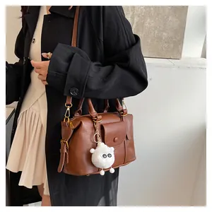 Dettaglio di una borsa Boston vintage marrone in ecopelle con un simpatico ciondolo agnello