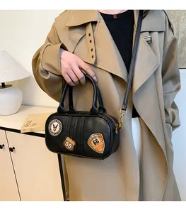 Detail of black cylinder handbag with vintage embroidery patches on a stylish trench coat