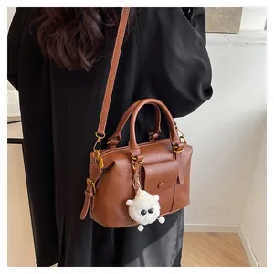 Dettaglio della borsa Boston marrone scuro con charm agnello e tracolla regolabile indossata