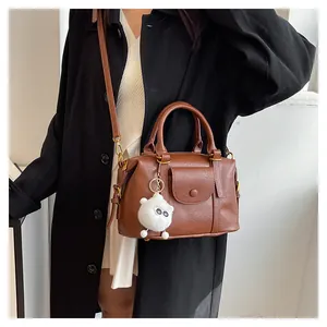 Dettaglio borsa Boston vintage marrone con trama litchi e pompon bianco