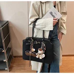 Detail of black tote bag with wavy edge featuring cute plush bear and bread pendants