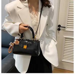 Detail of black pleated faux leather bag with yellow square buckle and gold hardware