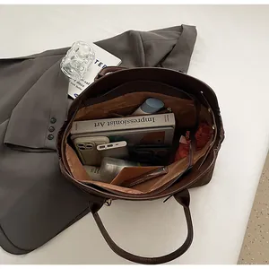 Deep brown leather tote bag interior showing large capacity with books and accessories